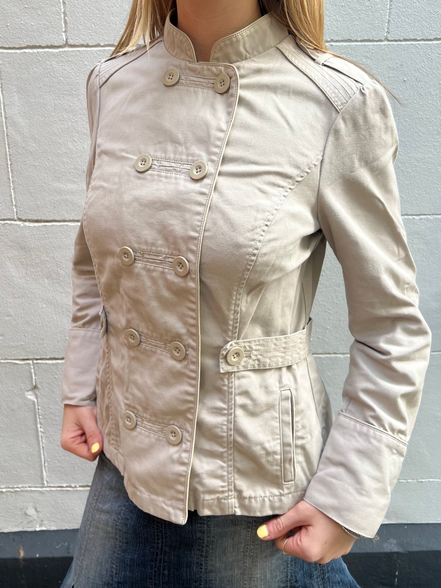 Beige jacket worn by a person against a gray wall
