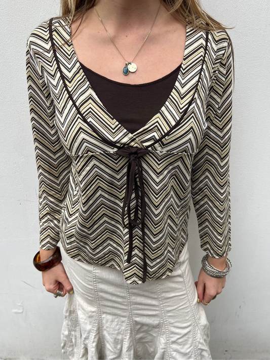 Person wearing a patterned blouse with a plain background