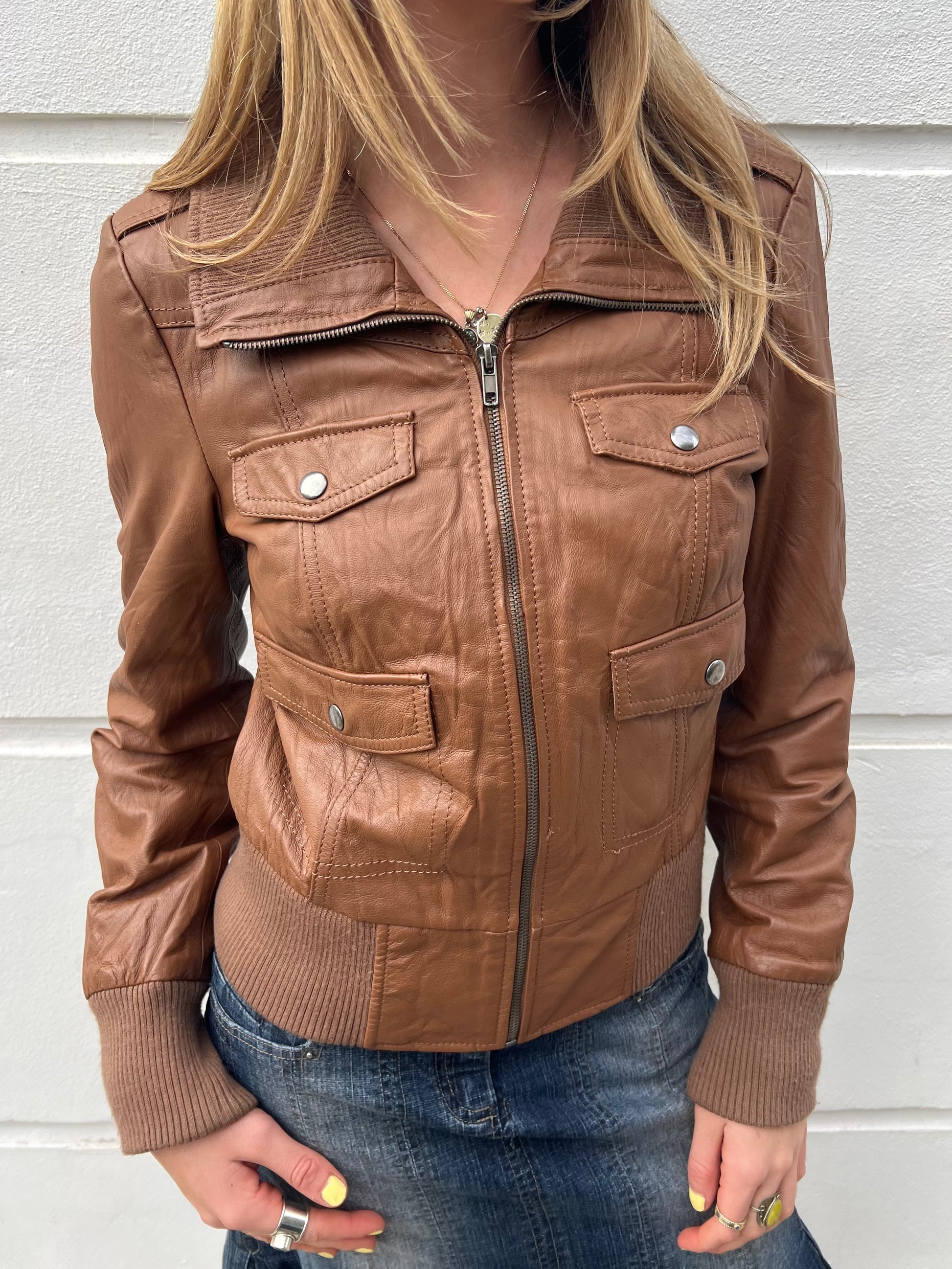 Brown leather jacket worn by a person against a light background