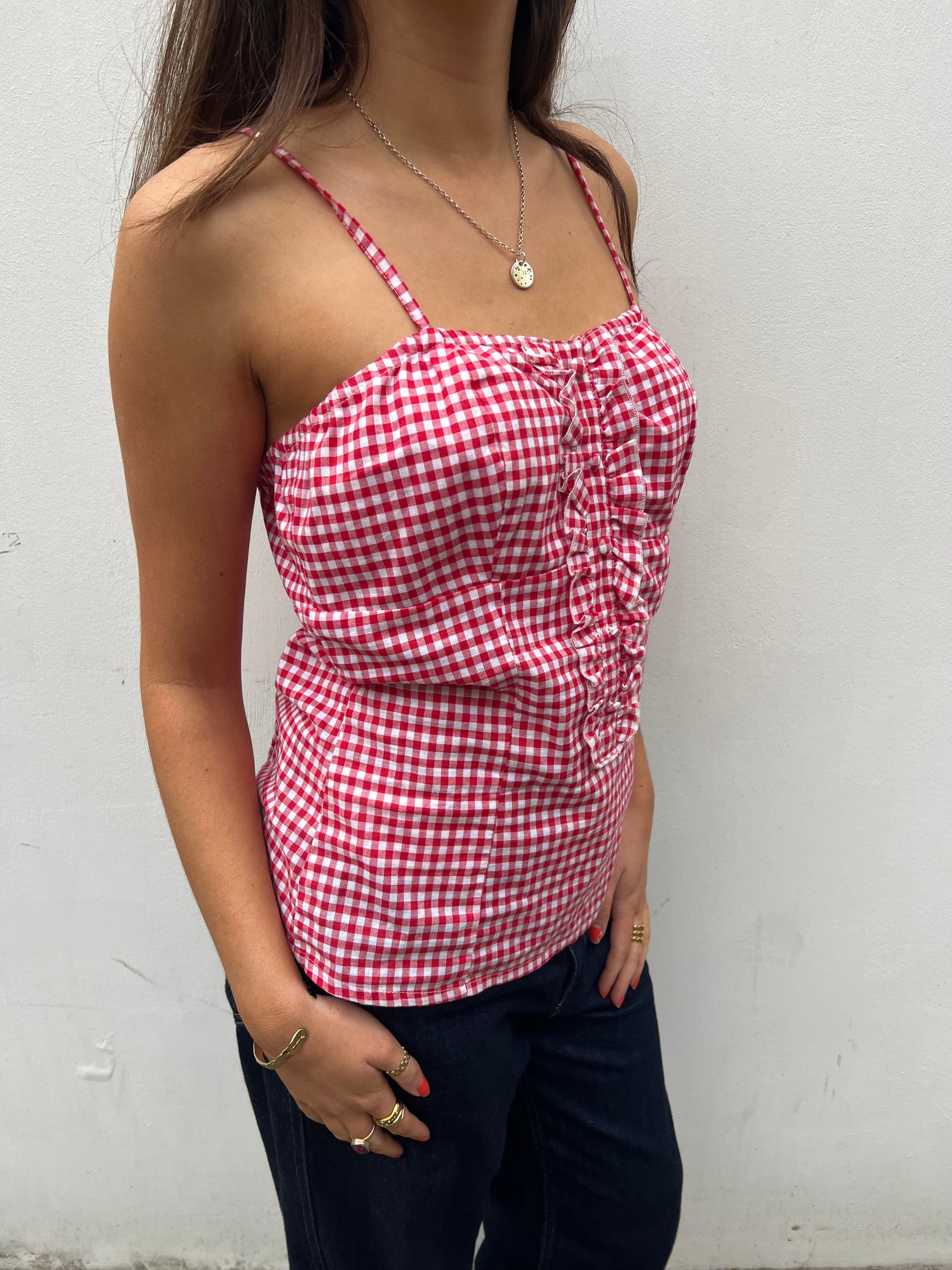 Person wearing a red and white checkered top against a white background