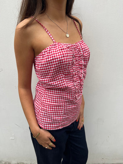 Person wearing a red and white checkered top against a white background