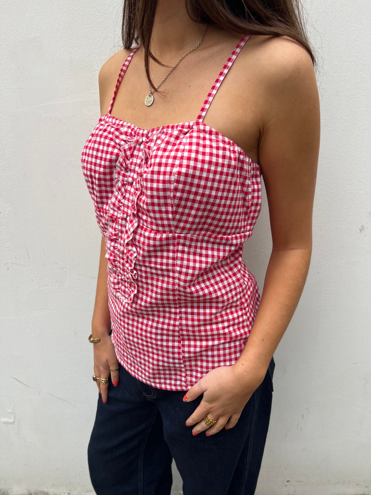 Person wearing a red and white gingham top against a plain background