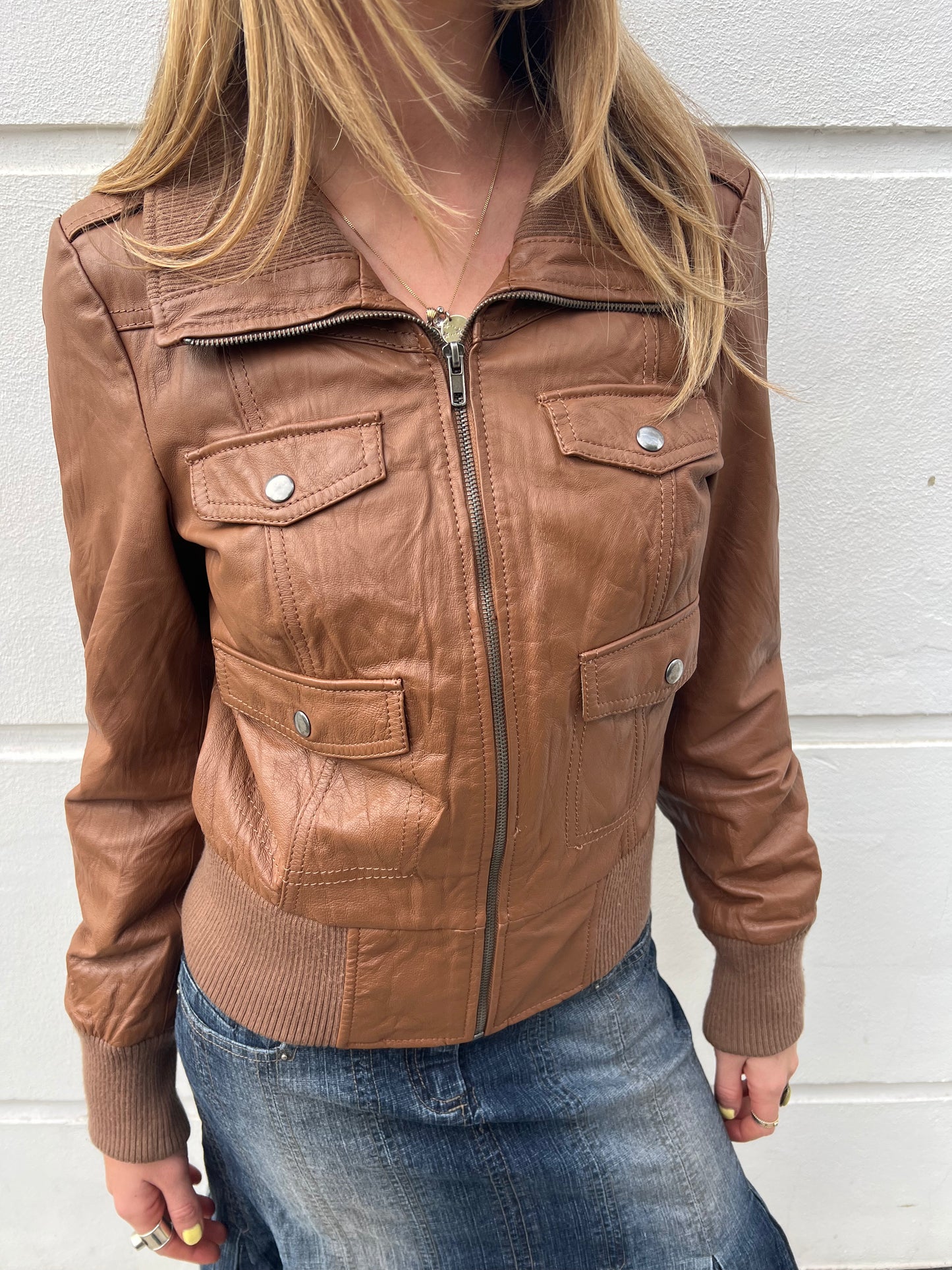 Brown leather jacket worn by a person against a light gray background
