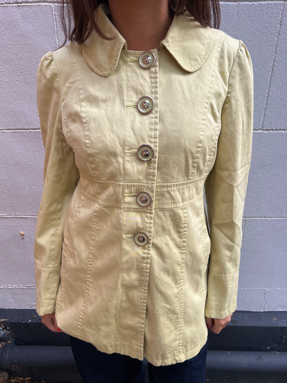 Light-colored jacket worn by a person against a gray wall.