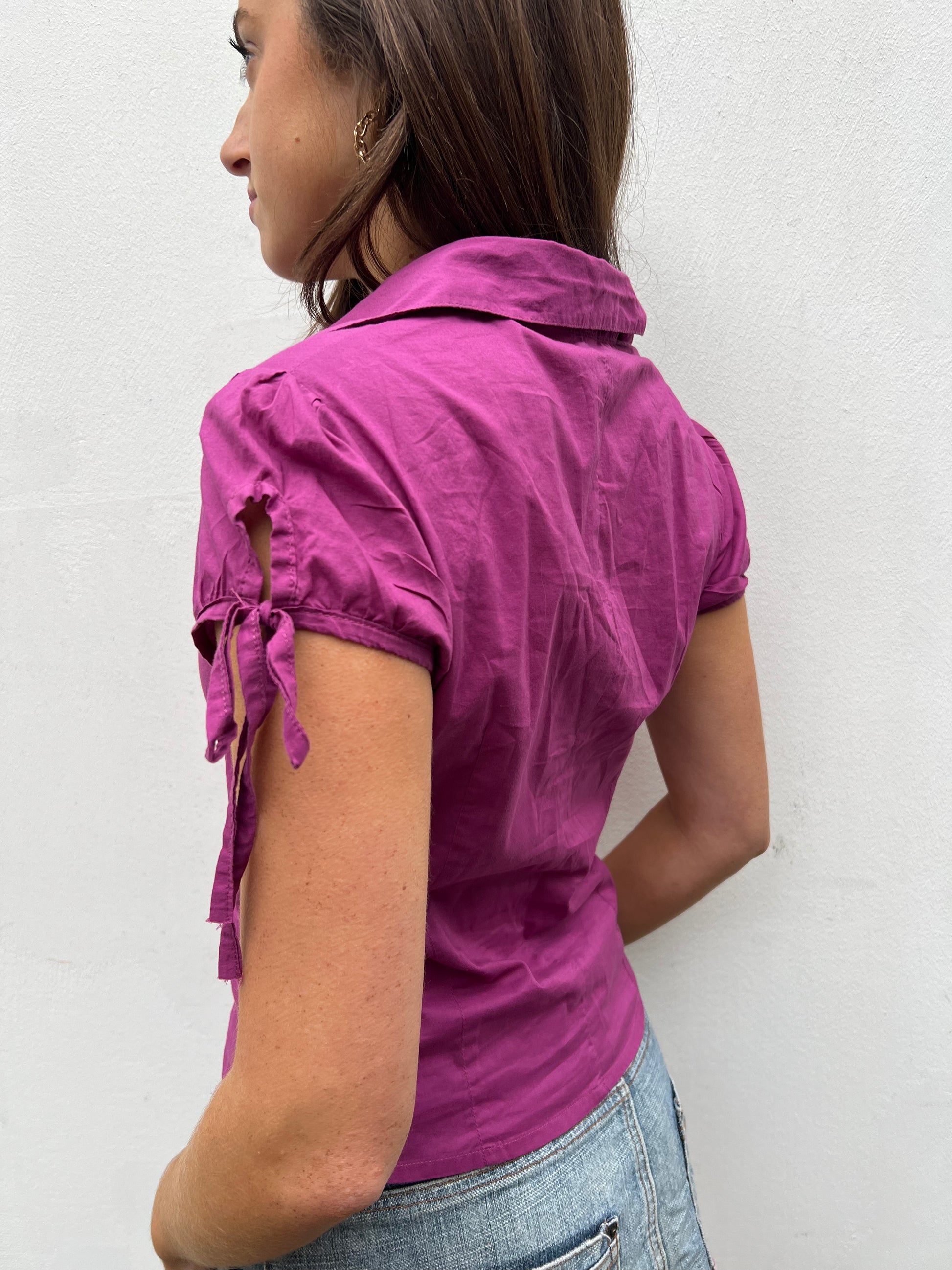 Woman wearing a purple shirt with ruffled sleeves against a white background