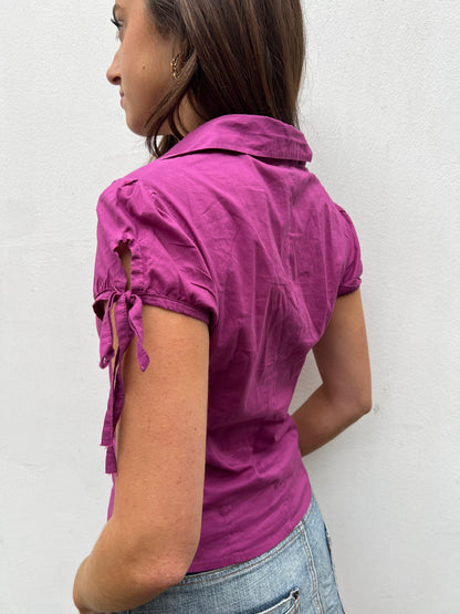 Woman wearing a purple shirt with ruffled sleeves against a white background
