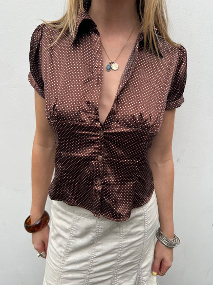 Woman wearing a brown patterned blouse with a white background