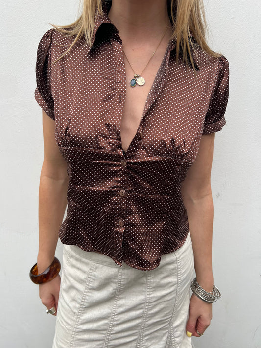 Woman wearing a brown patterned blouse with a white background