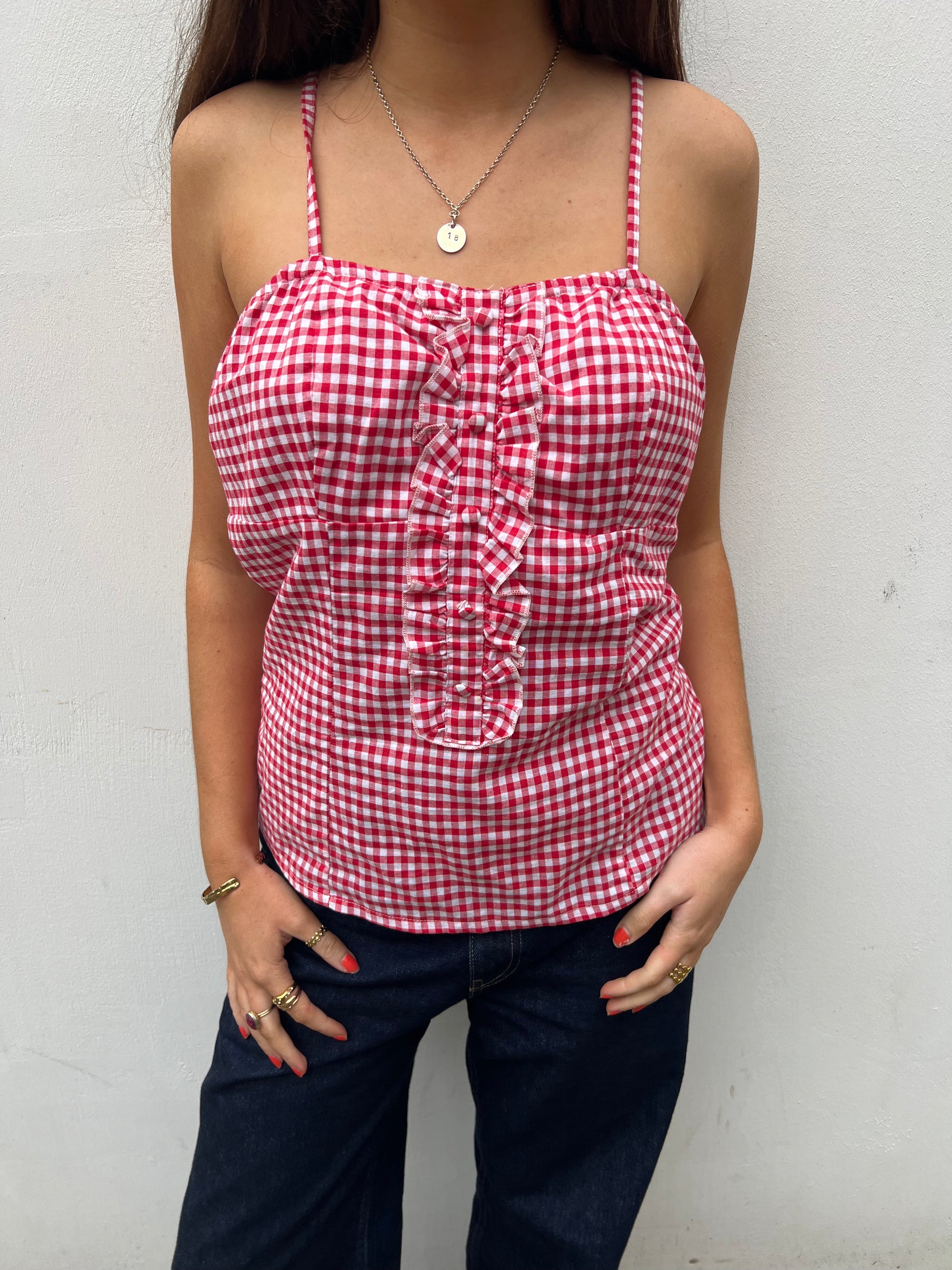 Person wearing a red and white gingham top with ruched details against a plain background