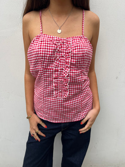Person wearing a red and white gingham top with ruched details against a plain background