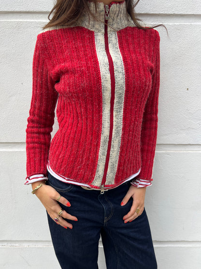 Person wearing a red and gray sweater with a white stripe against a light gray background