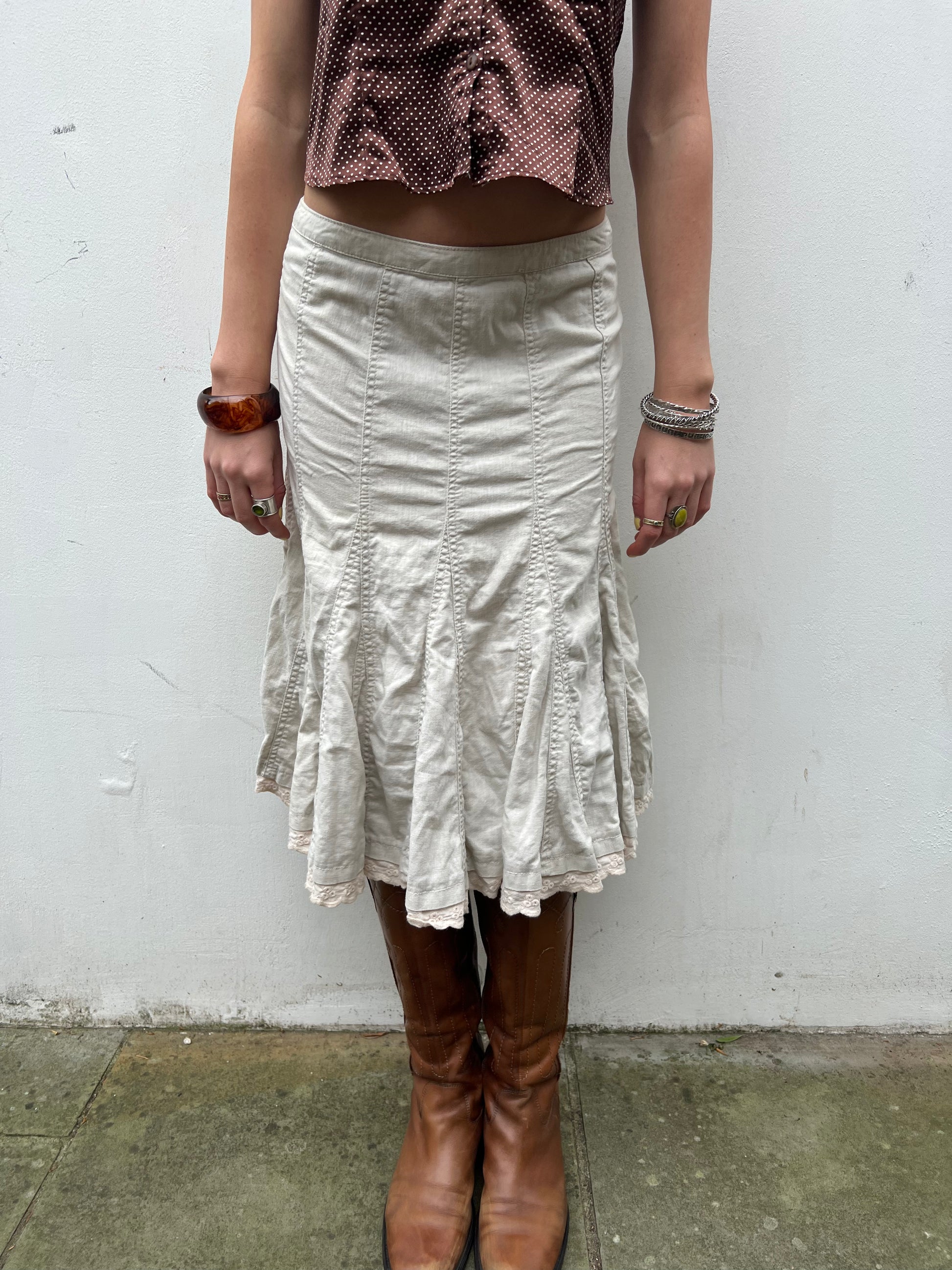 Person wearing a white skirt and brown boots against a plain background