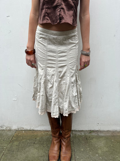 Person wearing a white skirt and brown boots against a plain background